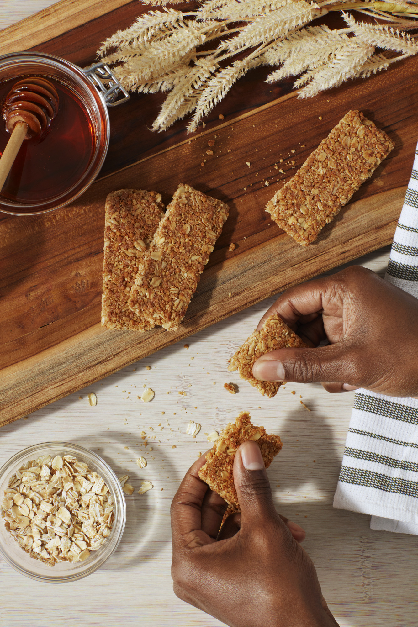 hands breaking a Nature Valley bar in half over a cutting board
