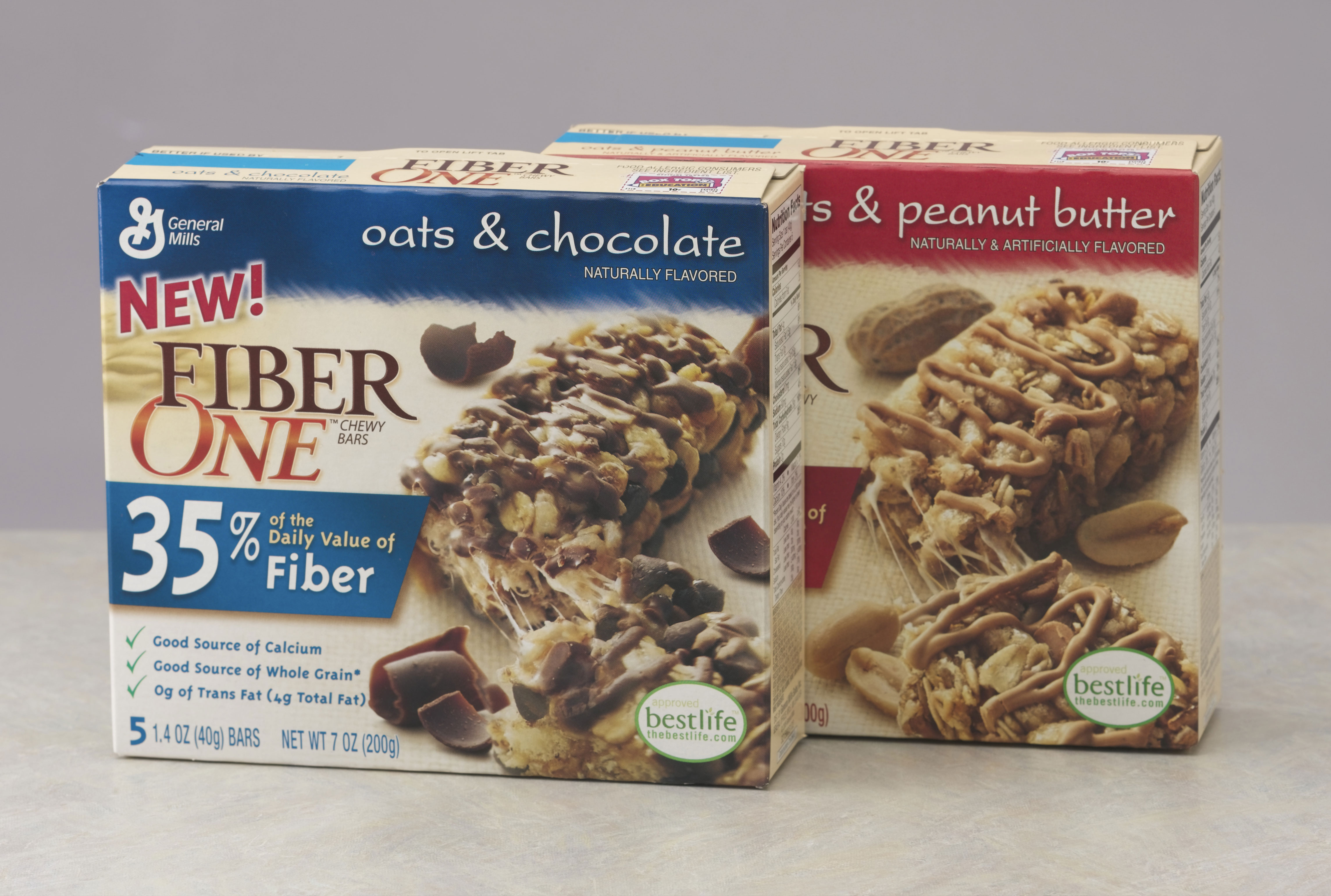 Two boxes of Fiber One Chewy Bars are displayed side-by-side on a plain background. The box on the left is the blue 'Oats & Chocolate' flavor, and the box on the right is the reddish-brown 'Oats & Peanut Butter' flavor.