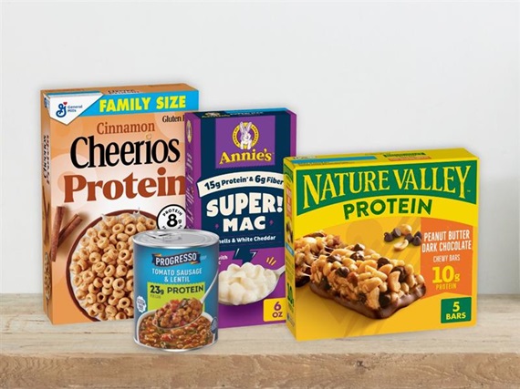Cheerios Protein Cinnamon Cereal, Annie’s Super! Mac Shells & White Cheddar, Nature Valley Protein Peanut Butter Dark Chocolate Bar and Progresso Tomato Sausage and Lentil Soup featured together on a kitchen counter.