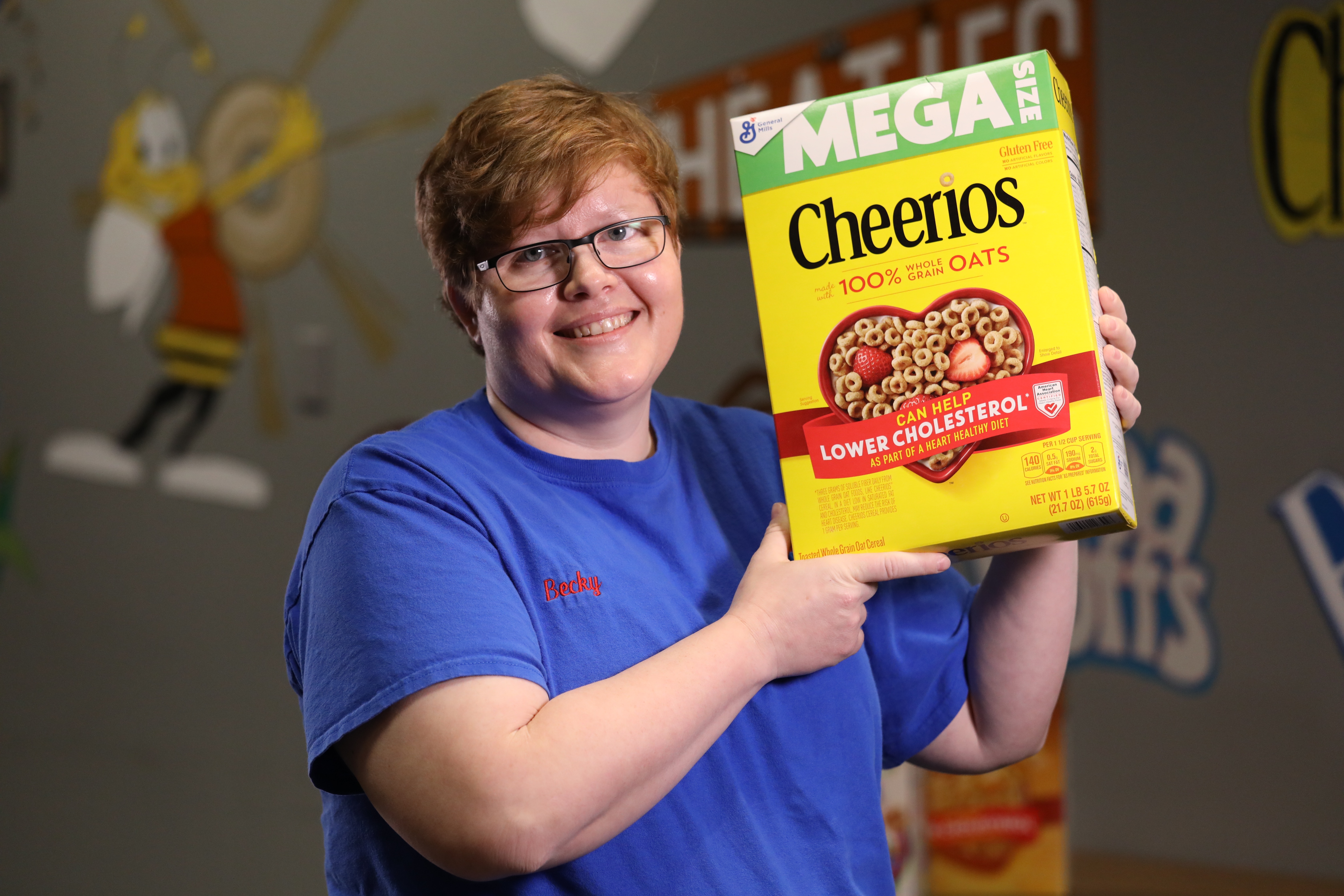 Employee holding box of Cheerios cereal